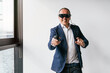 © Koldo_Studio - A businessman in a suit uses a VR headset and a controller, engaging with virtual reality technology in an office.