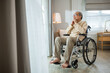 © sorapop - Lonely older thoughtful sad old man look outside windows in bedroom at retirement home, Asian senior man disabled feel depressed lonely sitting alone in wheelchair looking through window at hospital