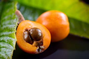 Canvas Print - Loquat fruit or Japanese medlars, Nispero, Eriobotrya japonica with leaves fresh ripe bio vegetarian food, medlar berries. Close up. On black background table. 