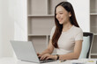 © MrAshi - Asian businesswoman working using a laptop computer Marketing report with calculator document on table Plan to analyze financial reports