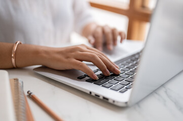 Wall Mural - A close-up image of a woman typing on keyboard, working on the computer at a table in a coffee shop.