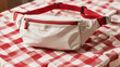 © Mudassir - A white fanny pack is lying on a red and white striped surface.