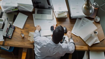 Poster - A focused man sitting at a desk covered with numerous papers, reviewing financial documents, A business man reviewing financial documents at his desk