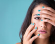 © peopleimages.com - Nail polish, manicure and portrait of woman on blue background for salon treatment, cosmetics and pampering. Spa, beauty and face of person for grooming, makeup aesthetic and wellness in studio