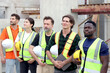 © Stella - Group of happy engineer worker team with safety vest and helmet standing with arms crossed in line at construction building site. Construction labor work at workplace. Teamwork unity and diversity