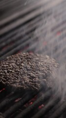 Wall Mural - Closeup vertical shot of the heavy white smoke rising up around a burger on a charcoal grill