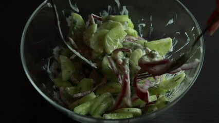 Wall Mural - freshness of a cucumber salad with red onion and yogurt dressing in a glass bowl in this closeup stock video