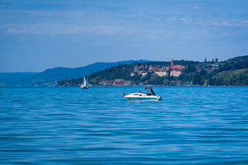 Wall Mural - Sailboats are seen floating in a body of water with a small town in the background.