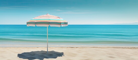 Wall Mural - Striped turquoise beach umbrella set in the sand of an uncrowded beach on a beautiful bright morning with copy space Summer vacation concept