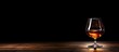© Gular - A copy space image of cognac or brandy placed on a vintage wooden table against a black backdrop