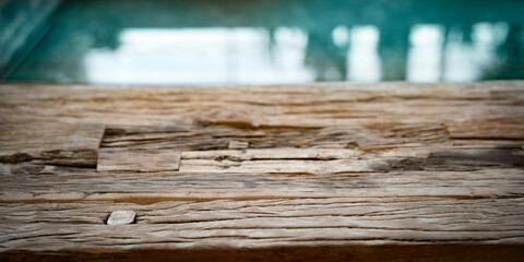 Wall Mural - Weathered old wooden texture in front of reflecting water surface. Shabby old wooden surface with inclusions and cracks. Background with short depth of field