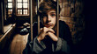 © Cliff - Young boy the teenager sitting behind bars in prison prisoner in a medieval jail with sad, pleading eyes of mercy