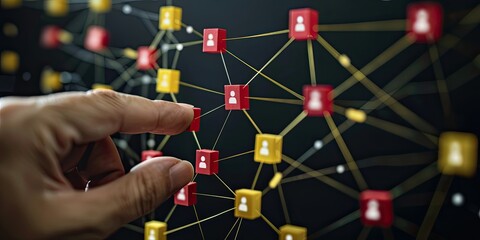 Wall Mural - A hand is connecting red squares with white icon people to yellow blocks on the right side of an uncluttered black background, representing network marketing and building visible connection