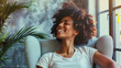 © mattegg - A young African American woman sits in a chair, smiling happily. She appears content and relaxed in her expression