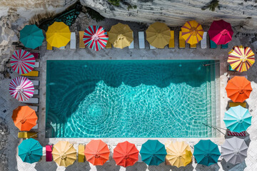 Poster - Aerial perspective showcasing a swimming pool adorned with vibrant umbrellas, creating a colorful and inviting atmosphere