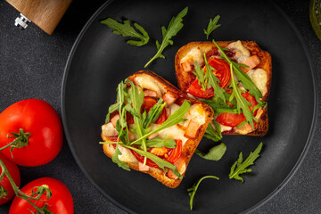 Wall Mural - Tasty crunchy toasts pizza. Fast food, modern variation of portioned quick made pizza on toast bread with tomato, bacon, mozzarella cheese and arugula, copy space