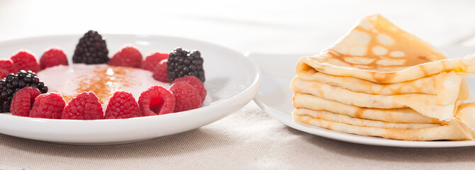 Wall Mural - Breakfast of raspberries and blackberries with yogurt and pancakes on table