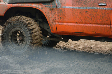 a red SUV in the mud accelerates to overcome obstacles. 