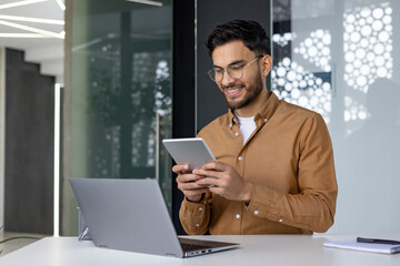 Poster - Young professional man using digital tablet at work in modern office setting