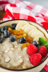 Wall Mural - tasty nutritious oatmeal with fruits and berries on a light stone background