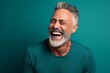 © Markus Schröder - Portrait of a happy man in his 50s laughing over soft teal background