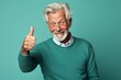 © Markus Schröder - Portrait of a tender man in his 60s showing a thumb up in front of soft teal background