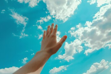 Wall Mural - Person Praising and Praying Holding Their Hand Up In The Air With A Blue Sky In The Background