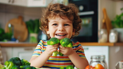 Canvas Print - A cheerful child in a striped shirt holding two pieces of broccoli in a kitchen, surrounded by fresh vegetables and smiling happily.