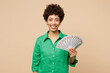 © ViDi Studio - Young woman of African American ethnicity wear green shirt casual clothes hold in hand fan of cash money in dollar banknotes isolated on plain pastel light beige background studio. Lifestyle concept.