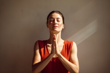 Sticker - Portrait of a merry woman in her 30s joining palms in a gesture of gratitude in front of minimalist or empty room background