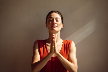 Canvas Print - Portrait of a merry woman in her 30s joining palms in a gesture of gratitude in front of minimalist or empty room background