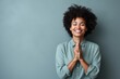 © Markus Schröder - Portrait of a blissful afro-american woman in her 40s joining palms in a gesture of gratitude isolated in minimalist or empty room background
