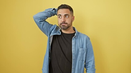 Wall Mural - Pensive young hispanic man in denim shirt stands doubtful, wrestling with unsolved question over sunny yellow cutout wall