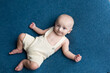 © Svetlana - a small child lies on a blue background. newborn boy in pants. baby's first photo shoot