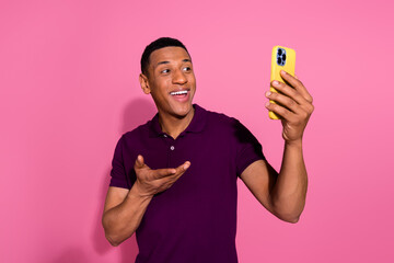 Poster - Photo portrait of attractive young man hold device video call dressed stylish violet clothes isolated on pink color background