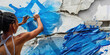 © Lila Patel - Electric Blue: A young activist paints a symbol of hope on a torn-down wall, their brushstrokes fluid and bold