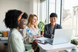 © Marko Geber - Diverse young female colleagues with laptop in modern office
