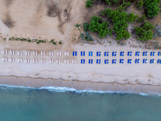 Wall Mural - Top down view of a beach with sunbeds a with sand beach and clear blue water in Greece