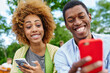 © BullRun - Positive african american friends with funny grimaces on face looking at front camera of modern smartphone and making selfie photos for blog spending together free time in urban setting