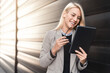 © Dorde - Cheerful business woman smiling at her tablet while walking outside.