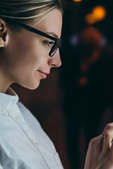 Wall Mural - Female standing at big display with smartphone in hand. Young woman reading information on mobile phone while using  public transport train schedule via application. Digital monitor with subway map