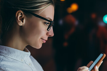 Wall Mural - female standing at big display with smartphone in hand. young woman reading information on mobile ph