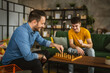 © Miljan Živković - Two male friends brothers play chess together at home