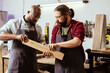© DC Studio - Manufacturer and apprentice wearing safety glasses selecting high quality wood materials. Cabinetmaker and colleague using protective equipment doing quality assurance on lumber piece