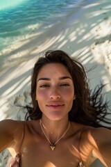 Wall Mural - Beautiful young woman is taking selfie resting on white sand beach