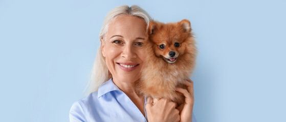 Canvas Print - Mature woman with Pomeranian dog on blue background, closeup