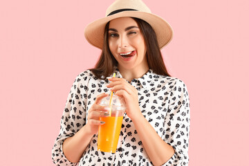 Wall Mural - Young woman with glass of juice on pink background