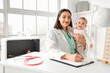 © Pixel-Shot - Female pediatrician with little baby writing in clipboard at hospital