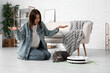 © Pixel-Shot - Emotional woman with cute cat, robot vacuum cleaner  and scattered litter at home