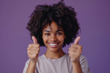 Poster - Photo of a happy black woman with afro hair wearing a casual t-shirt showing thumbs up on a purple background